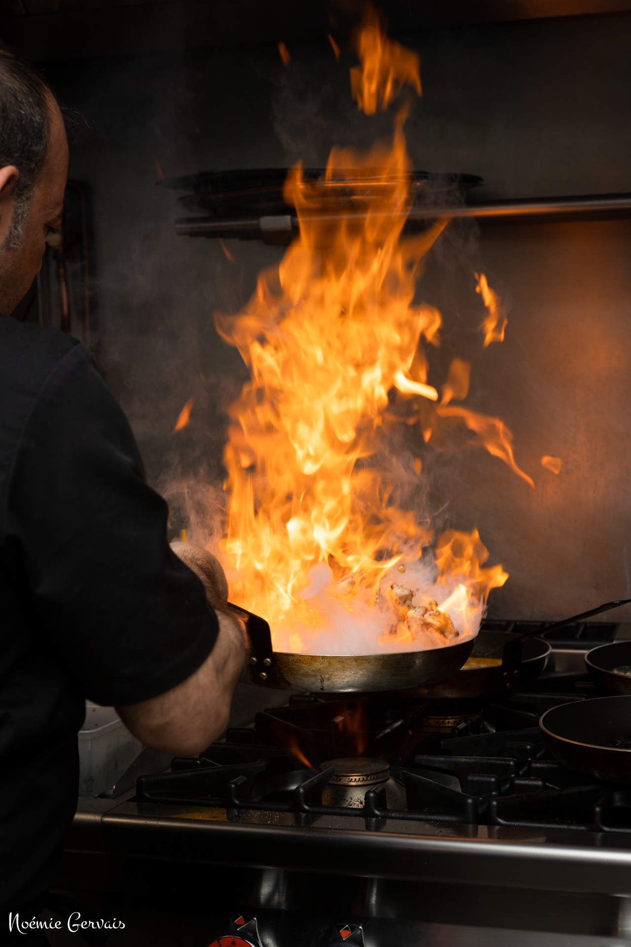 Cuisinier en train de faire flamber des pâtes à l'italienne